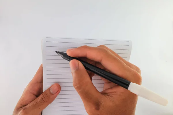 write on blank paper with a black ballpoint pen. hand holding ballpoint pen to write on white paper. notebook or blank sheet to be used for notes.