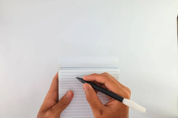 write on blank paper with a black ballpoint pen. hand holding ballpoint pen to write on white paper. notebook or blank sheet to be used for notes.