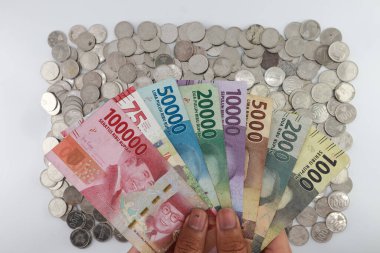 order of the Indonesian rupiah currency from smallest to largest. Banknotes 100000, 75000, 50000, 20000, 10000, 5000, 2000, 1000 rupiah. with the concept of holding hands. white background.