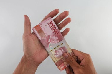 Indonesian rupiah currency. close up One hundred thousand rupiah. 100000 rupiahs. with the concept of being held by hand. receive financial assistance. white background. isolated, studio photography.