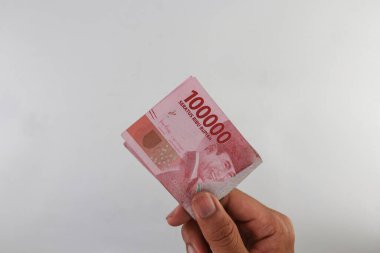 Indonesian rupiah currency. close up One hundred thousand rupiah. 100000 rupiahs. with the concept of being held by hand. receive financial assistance. white background. isolated, studio photography.