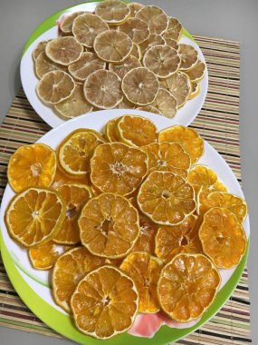 Kurutulmuş limon ve portakal cipsi güzel tabaklar üzerinde beyaz bir masanın üzerinde bambu peçetesi.