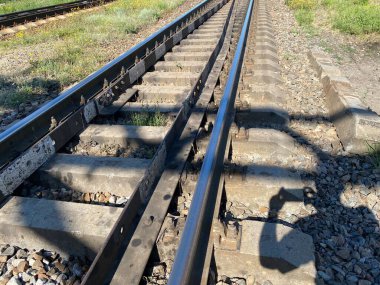 Railway with waggons on a field covered with green grass on a sunny day