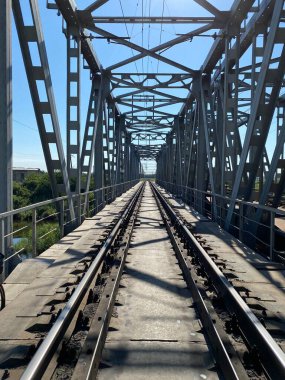 Metallic railway bridge in perspective with close-up rails