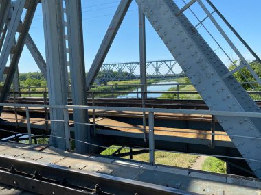 The railway bridge made of iron over the river still shows another bridge and blue sky