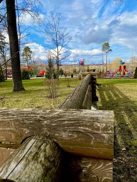 青空を背景に市公園内の木製フェンスや緑の草や木で遊び場 — ストック写真