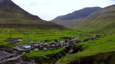 Aerial view of Gjogv village in Faroe Islands. Sunny day in summer. Amazing nature in Faroe Islands. Eysturoy Island. Birds on the footage. Faroese canyon.
