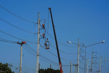 Elektrikçiler elektrik hatlarını onarmak için vinç kullanıyorlar..
