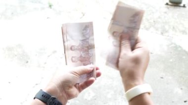 16 Ağustos 2024 'te Chiang Rai, Tayland' da iki elle banknot saymak..