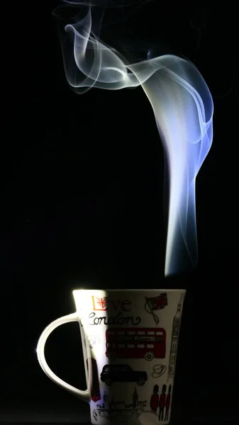 Bir fincan çayın yaratıcı fotoğrafçılığı siyah arka planda ortaya çıkar.