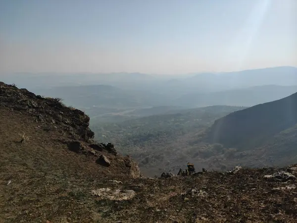 Gökyüzüne karşı yükselen tepeyi aydınlatan güneş ışığıyla görkemli bir dağ manzarası..
