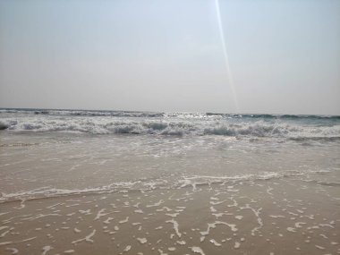 Güneşli sahil. Güneş ışığının ışıltısı altında parıldayan dalgalar..