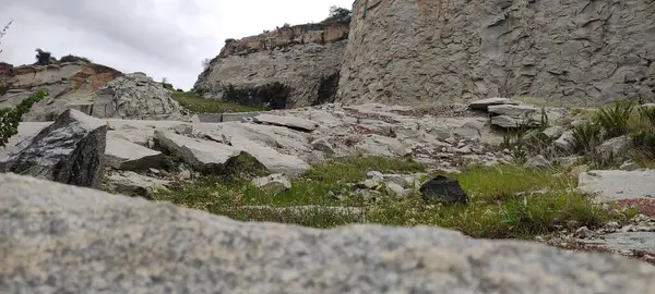Görüntünün altında, bir vadide kıvrılan bir nehir var. Dik bir kayanın nefes kesici manzarası var. Gökyüzünde bulutlar ve uçurumu kaplayan kalın yeşil bitki örtüsüyle manzara sakin ve güzel..