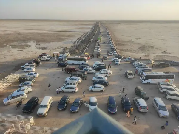 Geniş bir otopark yukarıdan görünen sayısız araba ve otobüsle dolu..