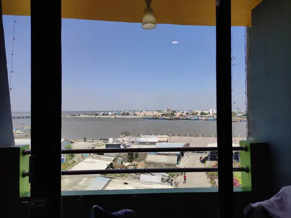 Resim, renkli teknelerle dolu hareketli bir limana bakan bir pencereden manzaralı bir görüntü yakalıyor..