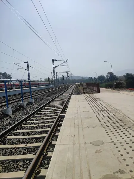 Görüntü, sağ tarafında tren rayı olan bir tren istasyonu platformunu gösteriyor. Platform boş ve etrafta hiç insan yok..