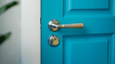 The girl inserts the key into the keyhole and opens the door