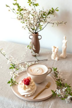 Cup with cappuccino and cake, spring flowers, morning concept, linen tablecloth, candles, woman's day