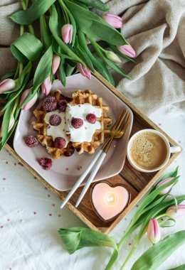 Breakfast in bad, waffles with berries, coffee, heart candle, Valentine's day concept