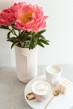 Cup with cappuccino, flowers peony, morning concept, soy candle, woman's day