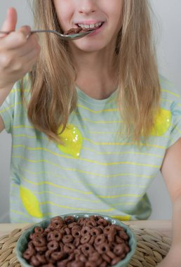 Küçük sarışın kız çikolatalı gevrek yiyor. 