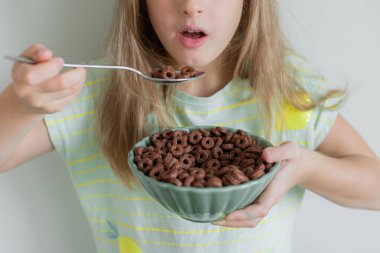 Küçük sarışın kız çikolatalı gevrek yiyor. 