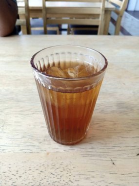 One glass of sweet iced tea on a wooden table