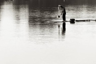 Fisherman is fishing with net on beautiful lake in the morning