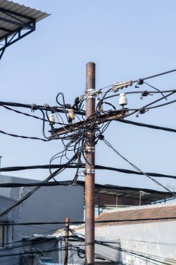 Direkteki dağınık elektrik kabloları. Jakarta caddesinde birbirine dolanmış elektrik kablolarıyla dolu bir kutup.