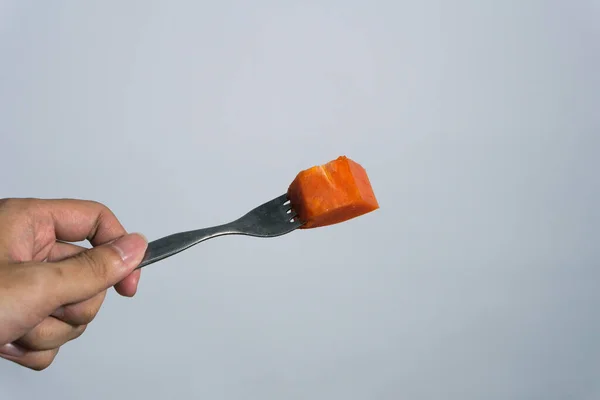 stock image the red papaya fruit tastes sweet on a fork with isolated background