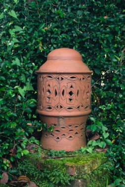 Kırmızı tuğlalı seramik bir fener. Yeşil çimenlerin arasında etnik bir dokunuş.