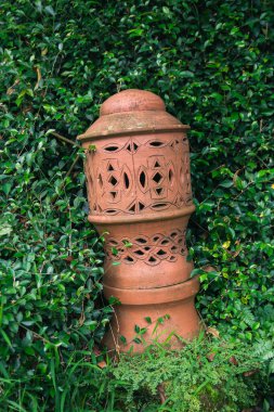 Kırmızı tuğlalı seramik bir fener. Yeşil çimenlerin arasında etnik bir dokunuş.