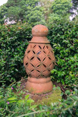Kırmızı tuğlalı seramik bir fener. Yeşil çimenlerin arasında etnik bir dokunuş.