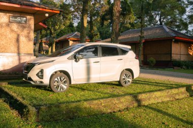 Bogor Mayıs 2023 - Nissan Livina arabası yemyeşil ağaçların arasına park edilmiş, aile tatili için huzurlu bir ortam yaratıyor.