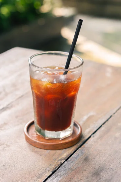transparent glass of ice black coffee or americano on wooden table with selective focus in cafe restaurant