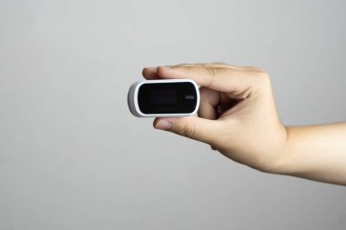 Beyaz arkaplanda izole edilmiş Nabız Oksimetrisi kullanırken insan parmağını kapat.