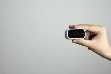 Beyaz arkaplanda izole edilmiş Nabız Oksimetrisi kullanırken insan parmağını kapat.