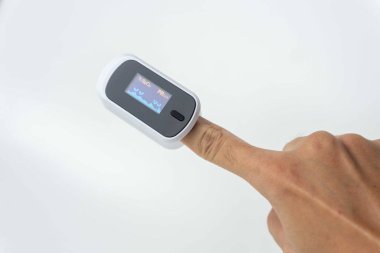 Beyaz arkaplanda izole edilmiş Nabız Oksimetrisi kullanırken insan parmağını kapat.