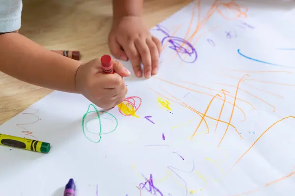 Asyalı bir çocuk beyaz kağıda pastel boya kalemleriyle resim çiziyor.. 