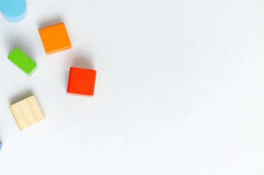 Beyaz arkaplanda çocukların gelişimi için renkli Montessori tarzı tahta blokların fotoğrafı, üst görünüm, en üstte kopyalama alanı