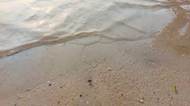 Yumuşak dalgalar kumlu sahili kapladı. Doğal soyut arkaplan ve doku