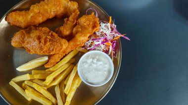 Kızarmış tavuklu şnitzel ve soslu patates kızartması.