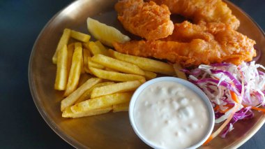 Kızarmış tavuklu şnitzel ve soslu patates kızartması.