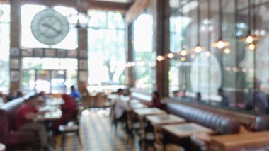 Restoranın arka planı bulanık. Ampul asılı ve geniş pencereli. Müşteri yemek bekliyor.