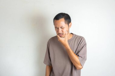 Puprle gömlek giyen genç adamın portresi yanağa dokundu. İzole edilmiş beyaz arka planda güçlü bir diş ağrısı var.