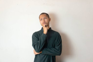 Sıcak kıyafetler giyen genç adamlar izole edilmiş beyaz arka planda bir şeyler düşünüyorlar.