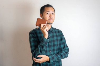 Yeşil flanel giyen genç adamlar, izole edilmiş beyaz arka planda kendine güvenen bir cüzdan tutuyorlar.