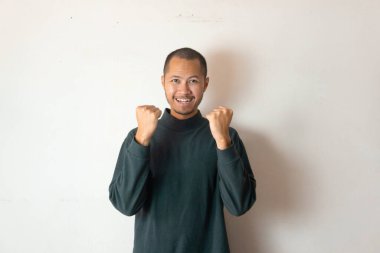 Yeşil kazak giyen genç erkekler, izole edilmiş beyaz arka planda gülümseyen bir jest yapıyorlar.