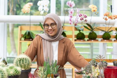 Küçük işletme sahibi kaktüs dükkanı gülen ve tesettürlü