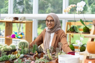 Küçük işletme sahibi kaktüs dükkanı gülen ve tesettürlü